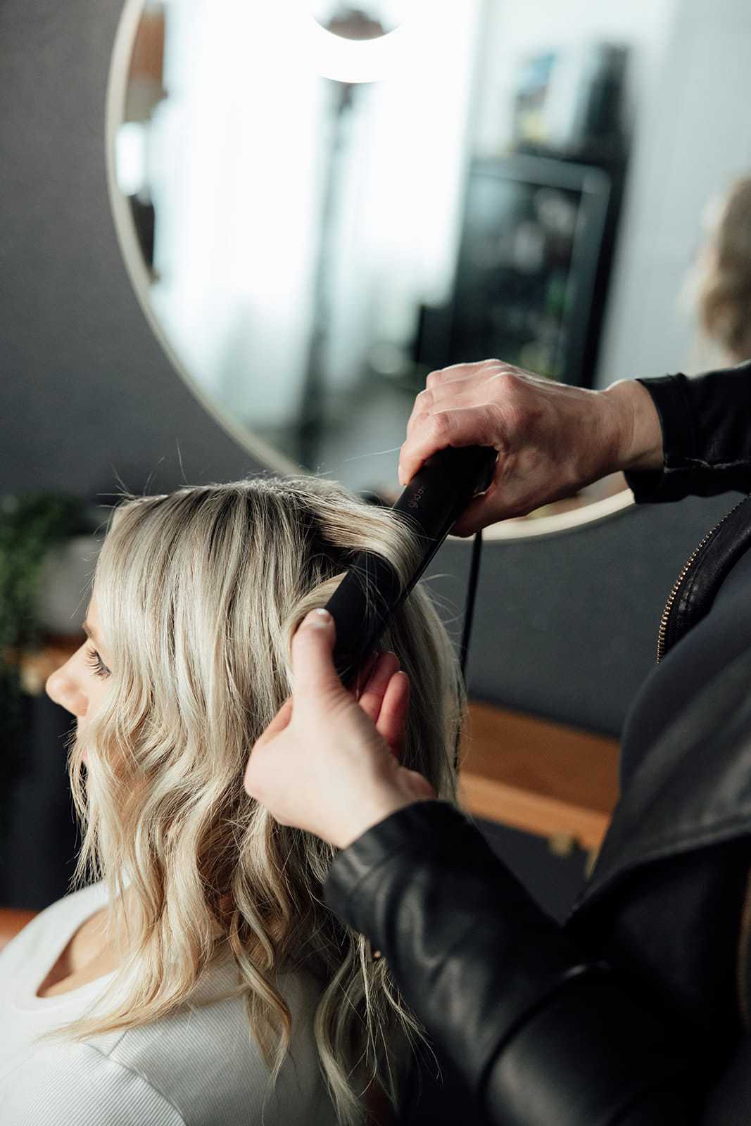 Woman getting hair styled with curling iron in salon.