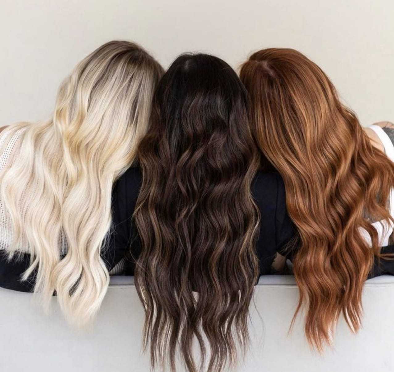 Three women with long blonde, brunette, and red hair sitting with backs to the camera.