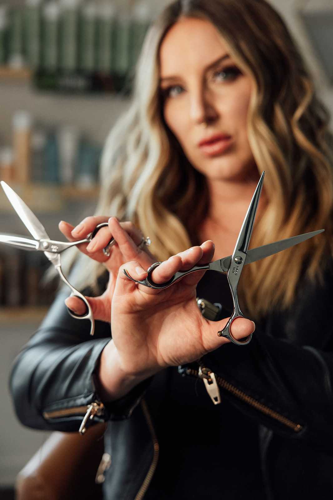 Hair stylist showcasing professional scissors in a salon setting.