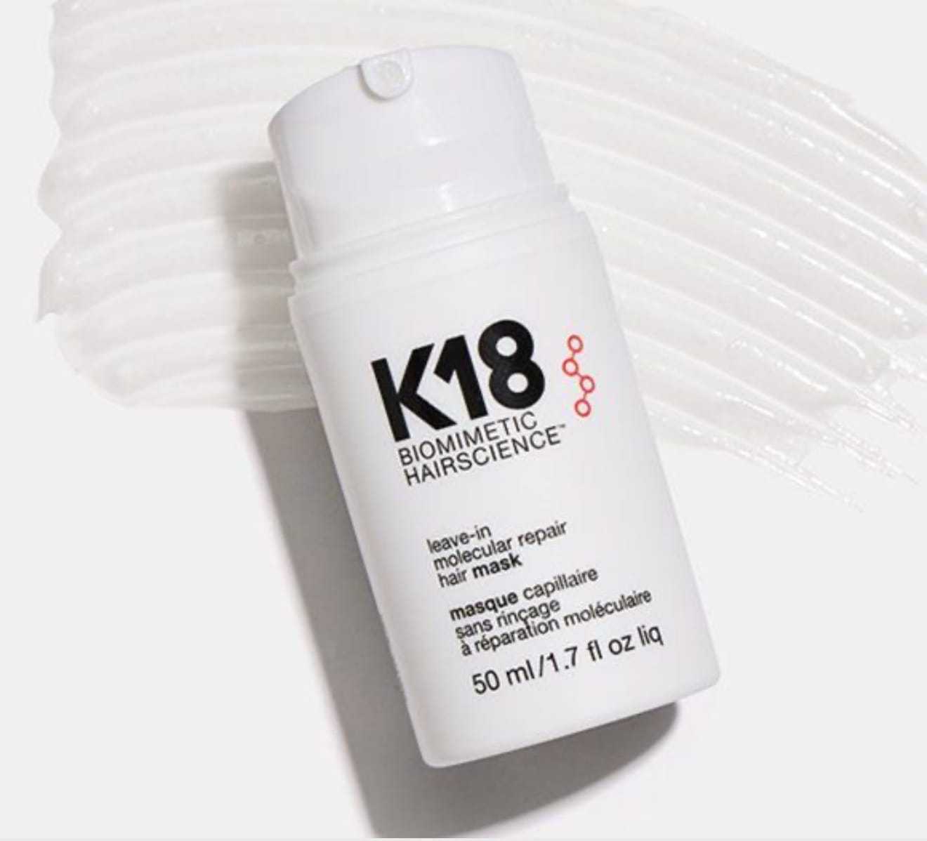 K18 leave-in molecular repair hair mask bottle on a smeared white cream background.