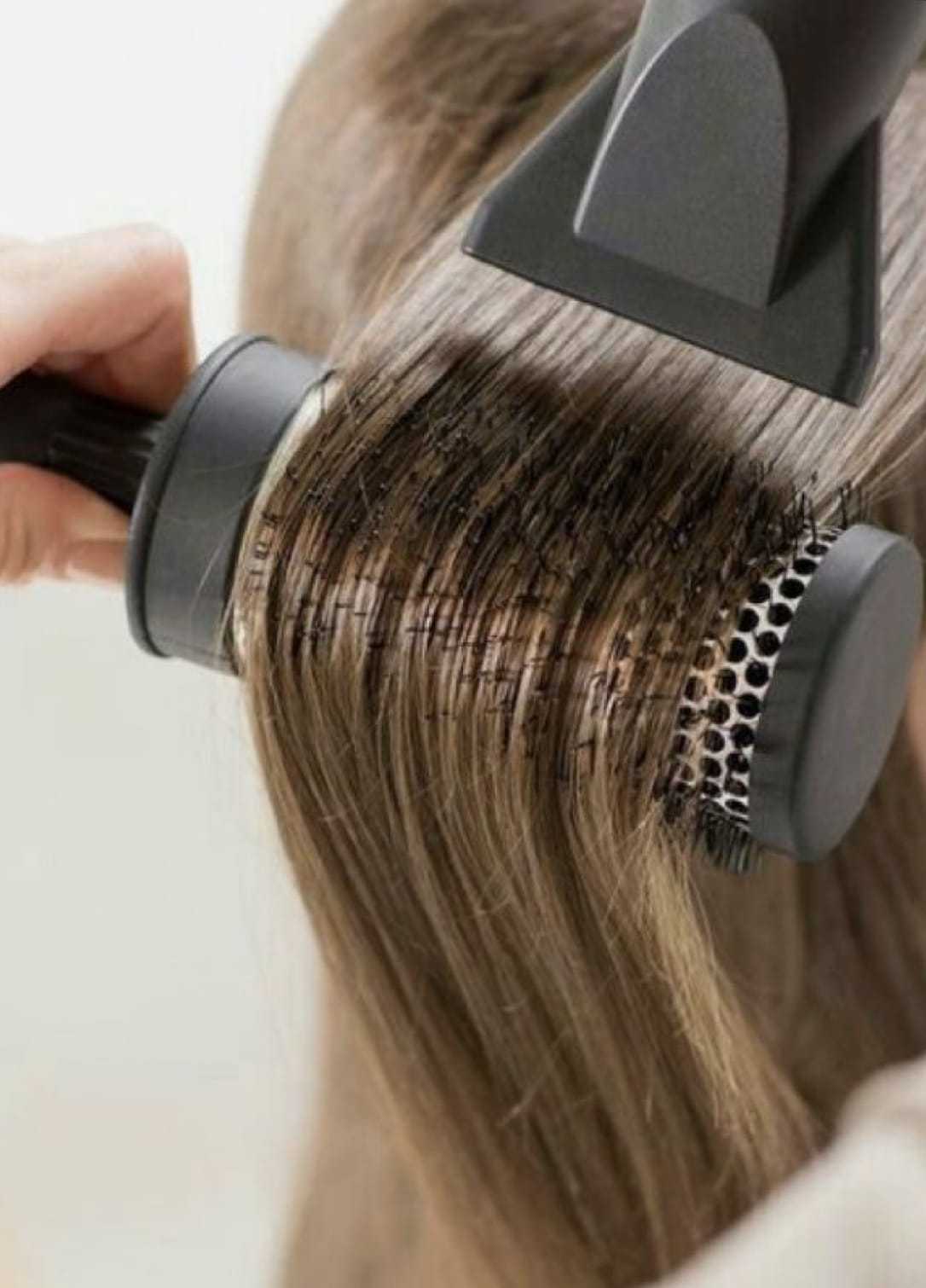 Styling hair with a round brush and blow dryer for smooth, straight finish.