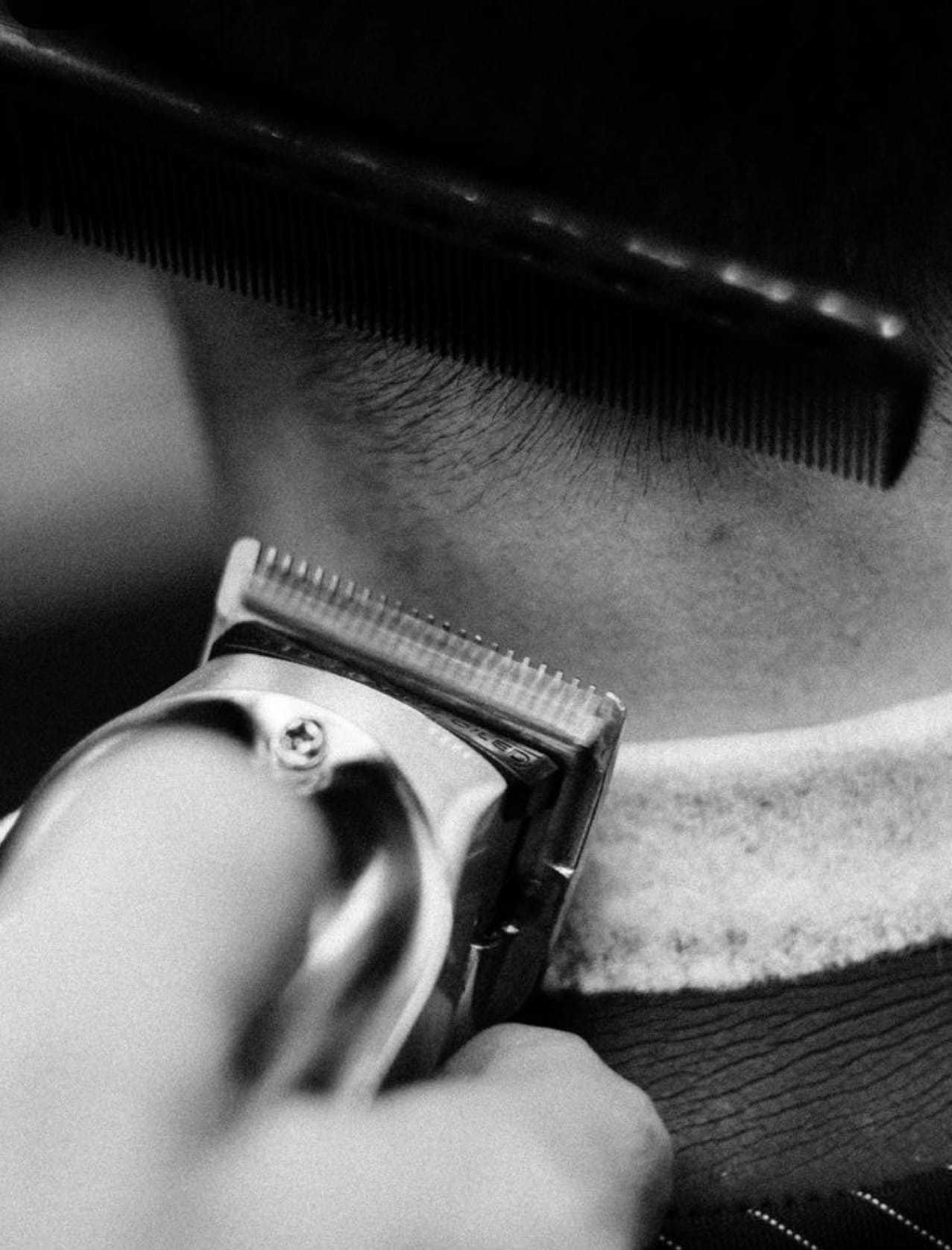 Barber using clippers to trim hair with a comb for precision.